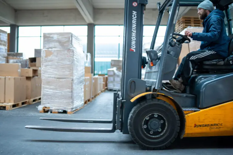 Mitarbeitender fährt einen Gabelstapler durch die Lagerhalle.