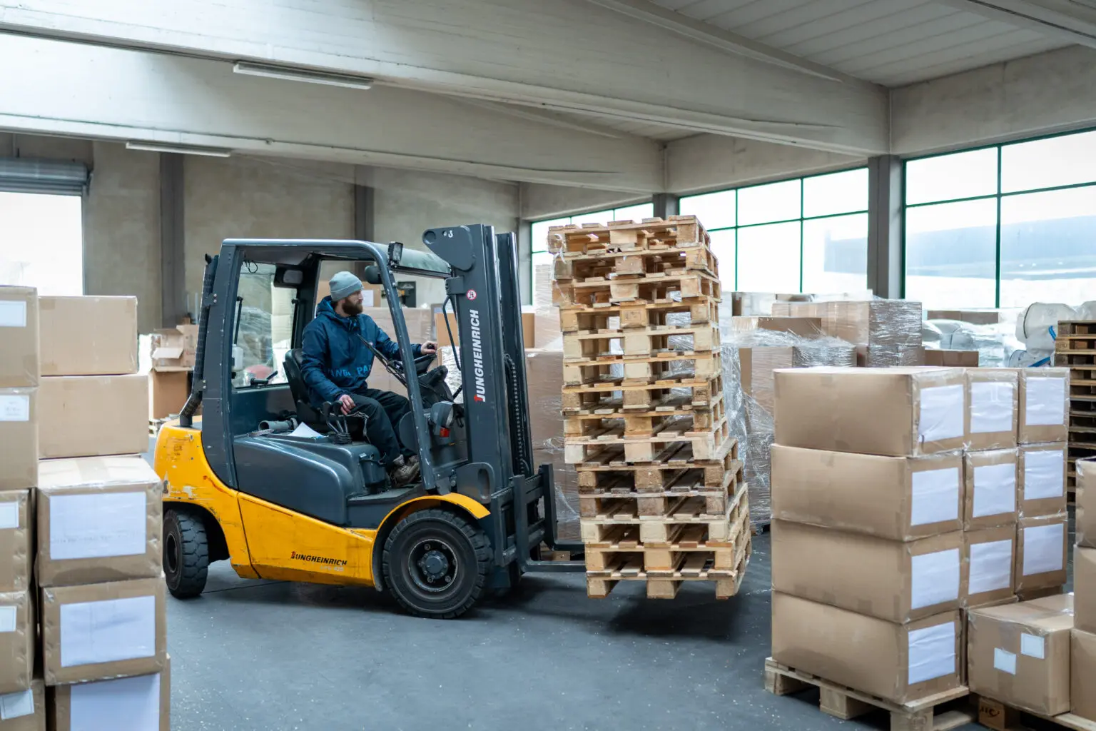 Fahrer bewegt mehrere leere Paletten mit einem Gabelstapler.