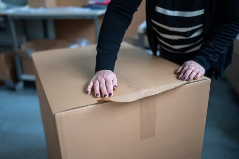 Hände beim Andrücken eines Kartonverschlusses.