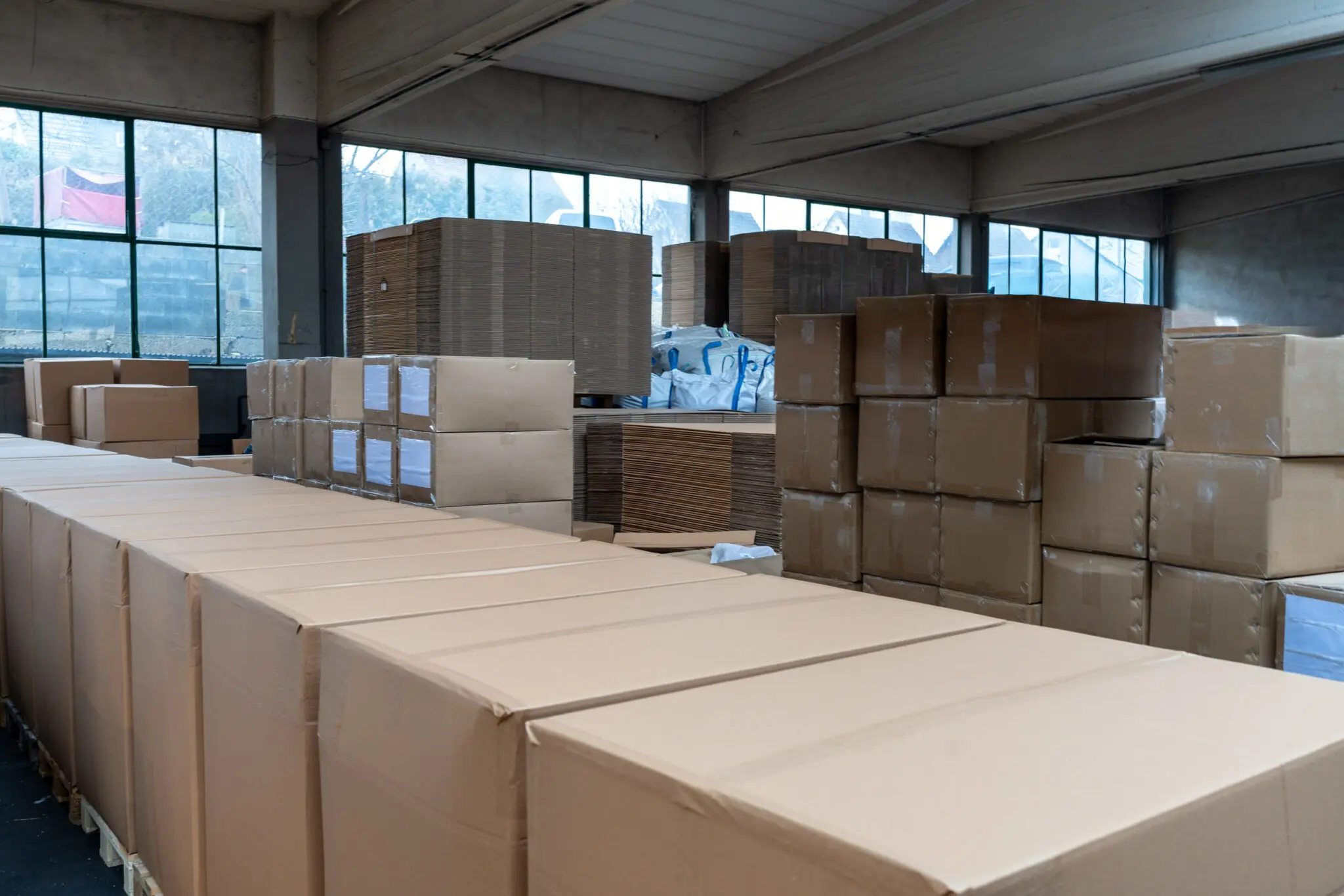 Stapel aus Kartons und Paletten in einer Lagerhalle.