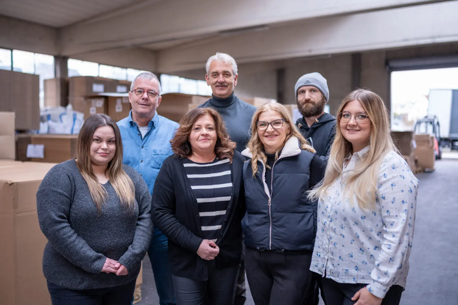 Sieben Mitarbeitende stehen gemeinsam in einer Lagerhalle.